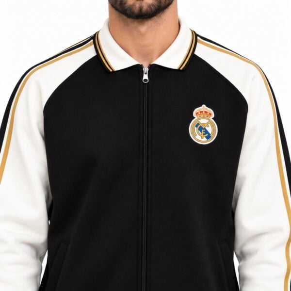 Real Madrid track jacket close-up showing tipped cream collar gold and black taping and embroidered club crest