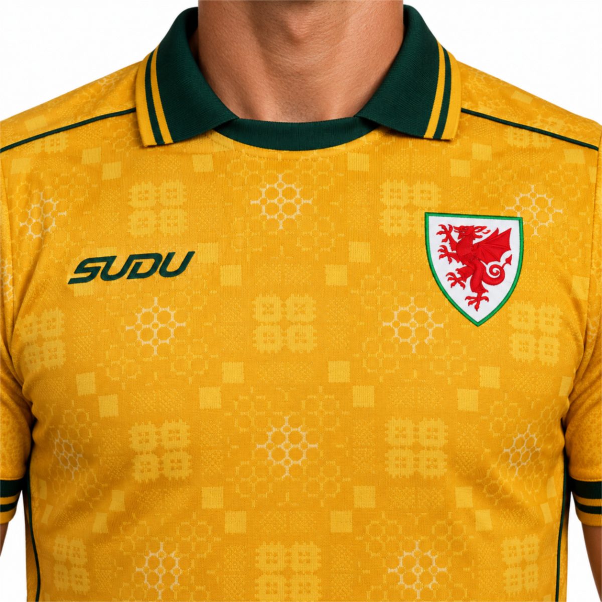 Wales away jersey close-up of the red dragon crest green collar with yellow tipping and tonal quilt pattern - UAE SPORT STORE Chest close-up of the yellow Wales shirt with green trim, a red dragon crest and geometric patterns.