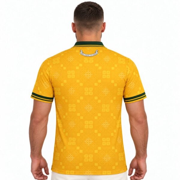 Rear of the yellow Wales shirt with geometric patterns, green sleeve trim and a small curved graphic below the collar.