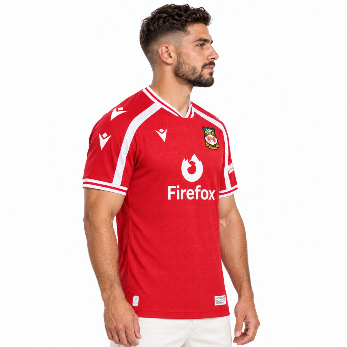 Wrexham home jersey 2026 2027 angled view red with tonal triangle jacquard pattern - UAE SPORT STORE Angled view of the red Wrexham shirt with white Firefox lettering and sleeve trim.